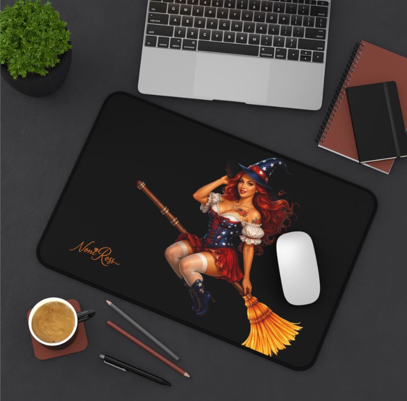 Large desk mat with witch artwork displayed in workspace with laptop and coffee cup setup